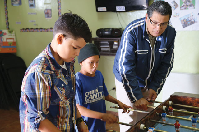 Father Alexis Zúñiga, S.T. plays foosball with boys at the Outreach Center for My Neighborhood.