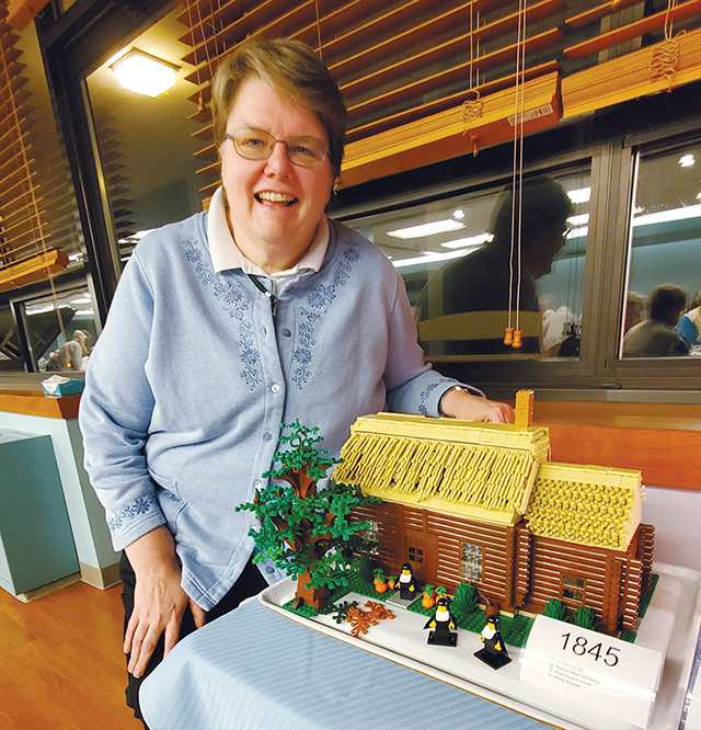Sister Elizabeth A. DeMerchant, I.H.M. displays a log cabin scene made of Legos, which she created to show the early history of her religious community.